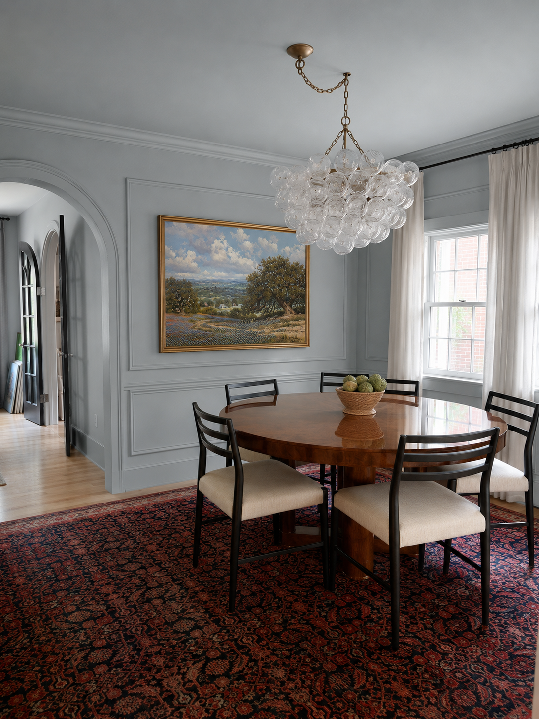 blue living room with picture frame molding and landscape art with bubble glass chandelier and red and blue persian rug
