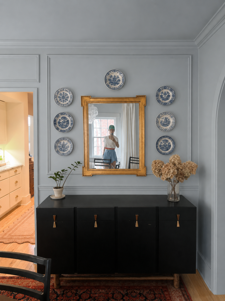 dining room with picture frame molding, red and blue persian rug and walls painted in farrow and ball's Parma Gray with blue and white plate wall and gold-framed mirror